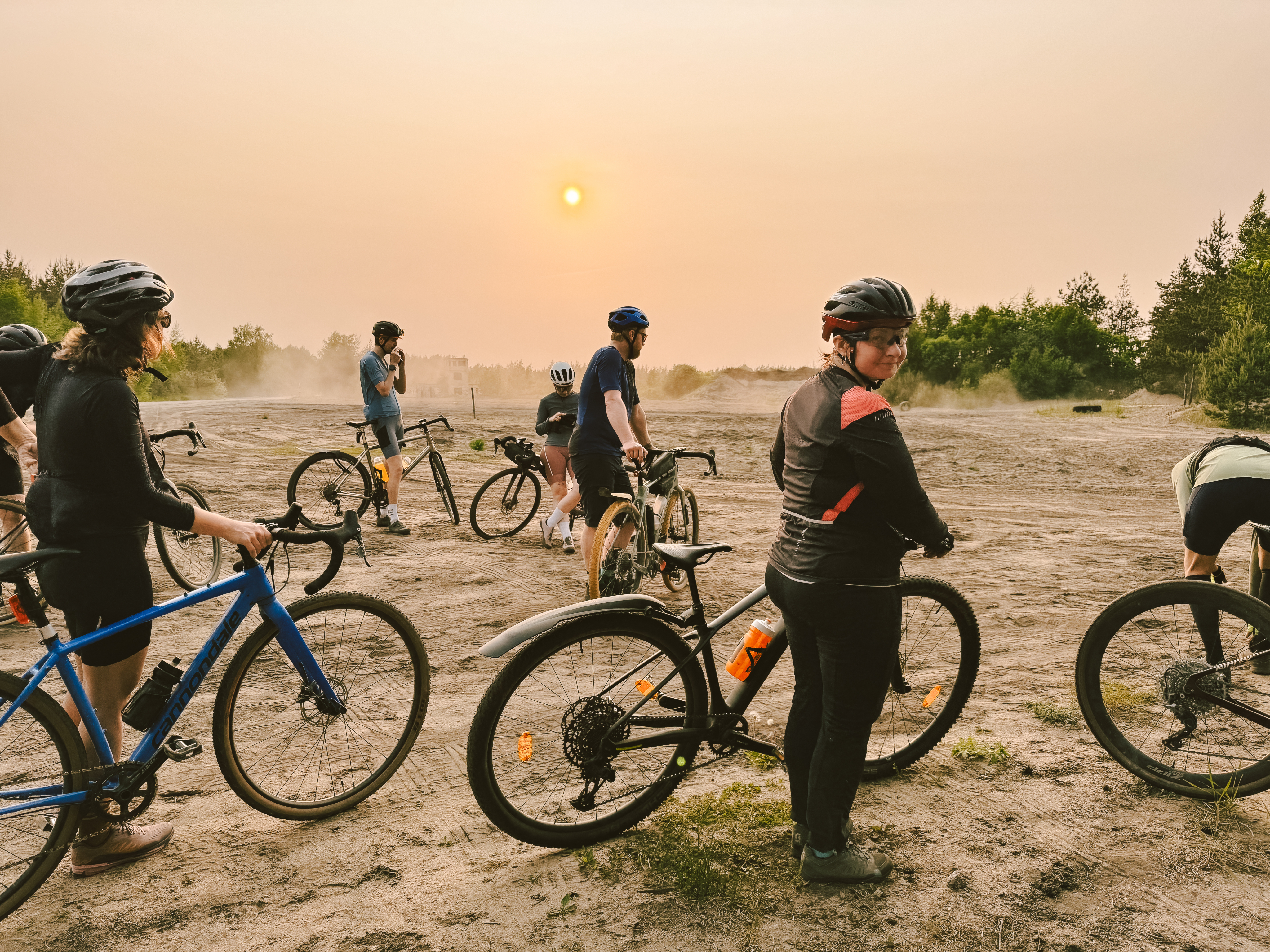 White Mediterranean-style house with a terracotta roof, surrounded by lush greenery and partially obscured by vibrant red-orange flowers in the foreground